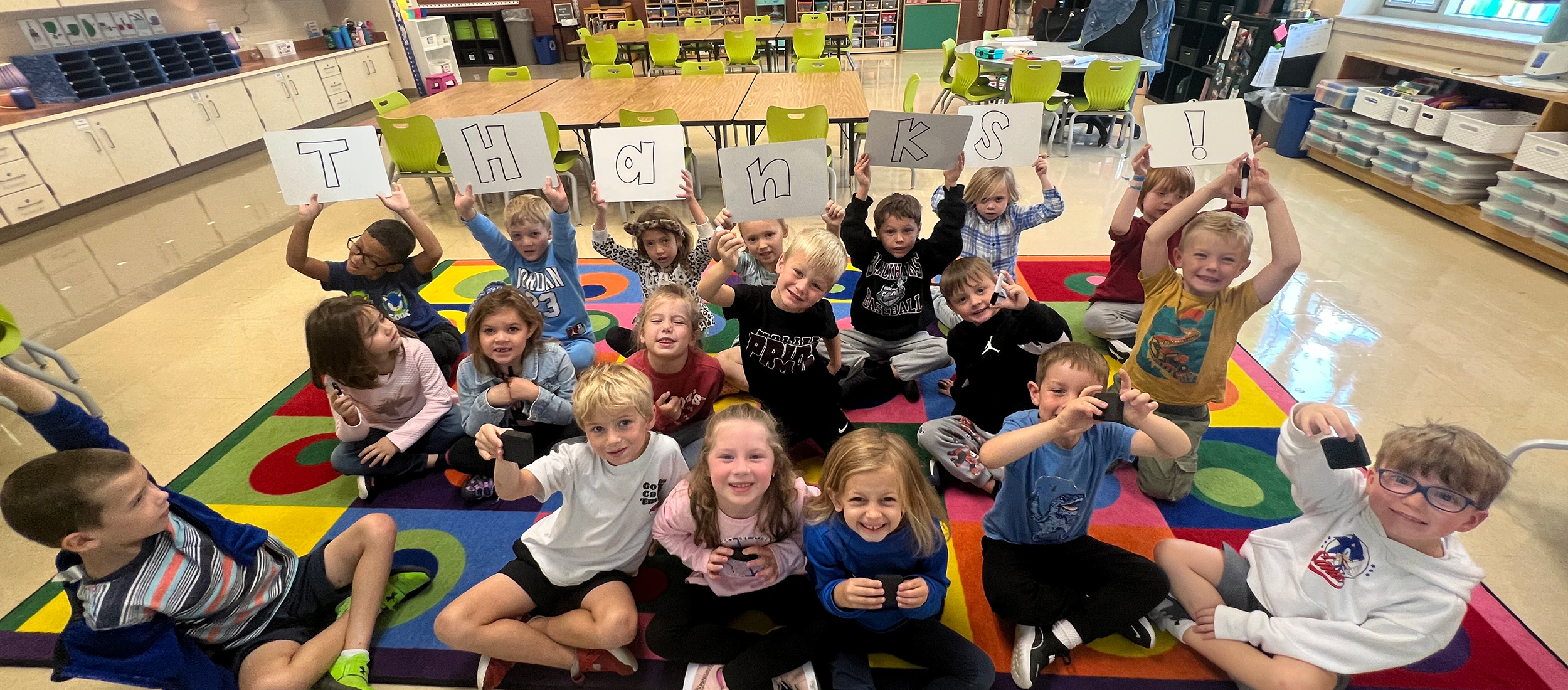 a classroom of students holidng signs that read Thanks