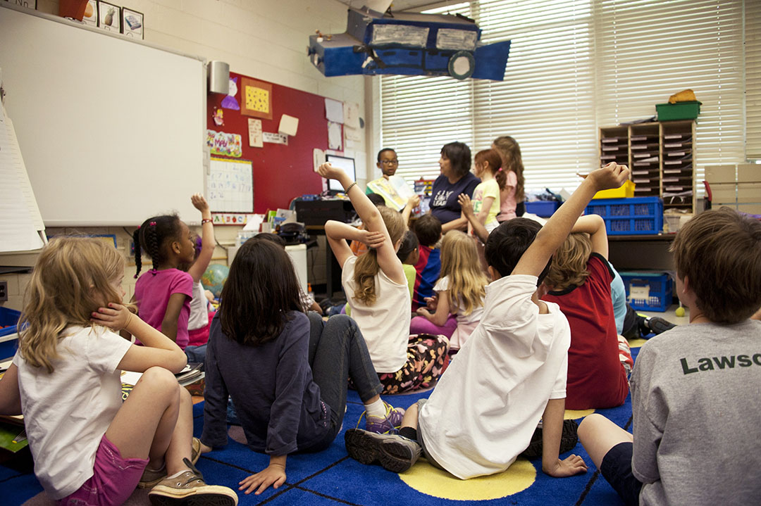 students in a classroom raising hands